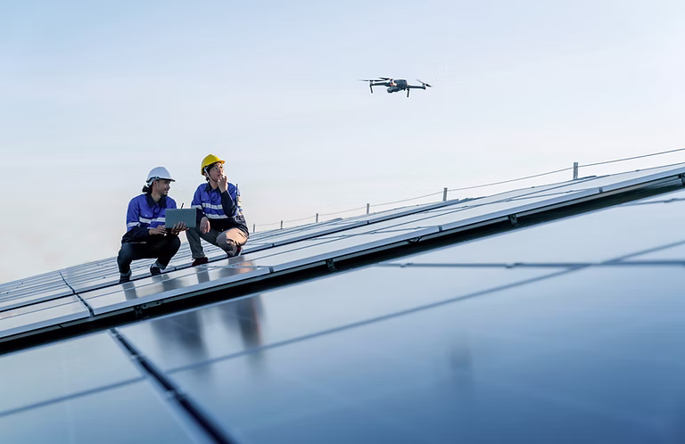 Crew on a solar array roof directing a survey drone