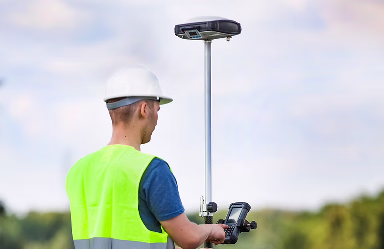 Surveyor operating a GNSS rover on site